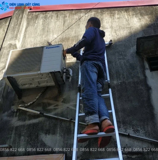 Thợ đang dùng đồng hồ đo áp suất và nạp gas điều hòa.